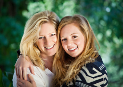 Mother and Daughter hugging portrait outside with greenery