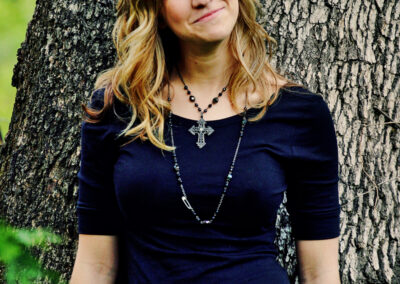 Senior girl standing in front of a tree looking up and smiling