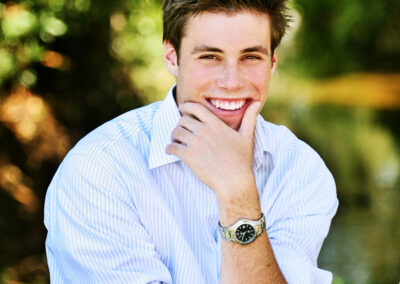 Senior boy posing with his hand below his chin and smiling