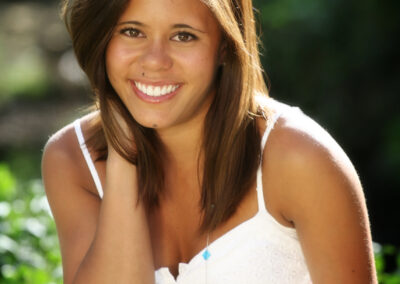 Senior girl posing with her hand below her cheek outside smiling