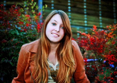 Senior girl headshot behind red floral background smiling