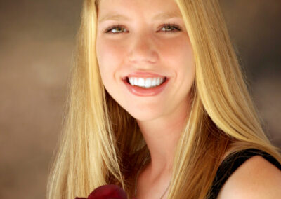 Senior girl smiling posing for a headshot holding a rose