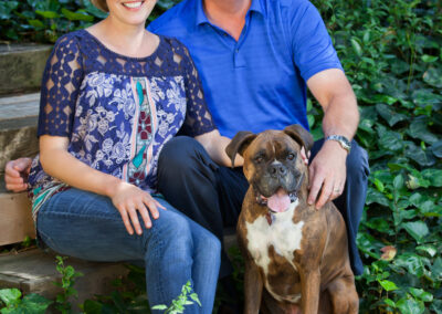 Man and woman sitting at the bottom of stairs with their large dog posed sitting in front of them