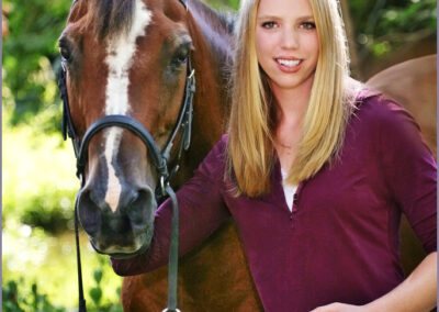 Outdoor session of a young woman posing standing next to her horse