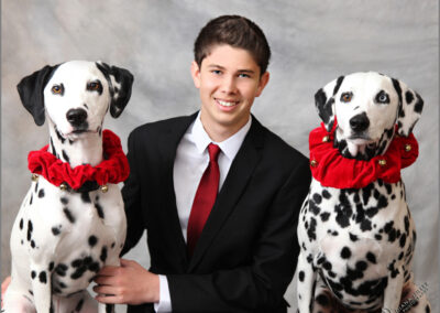 Matching portraits session of teenage boy between his two Dalmatian dogs