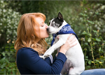 A Woman kisses her blind senior dog in outdoor photography session