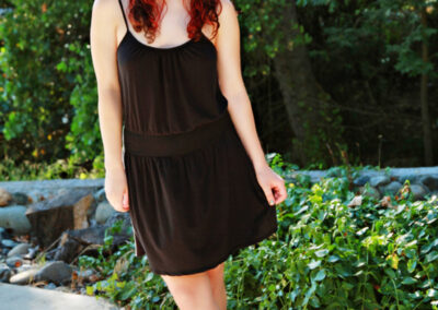 Senior girl posed standing legs crossed with nature greenery in the background