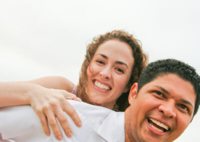 Engagement Session at Carmel Beach, CA Couple wearing all white in a loving piggyback pose