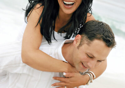 Couple playing in all white attire in a loving piggyback embrace