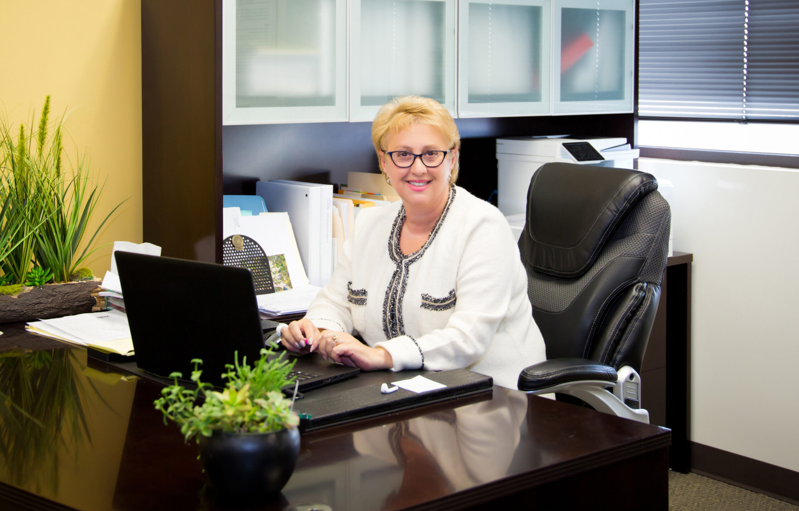 Woman sitting at desk in a office smiling at the camera